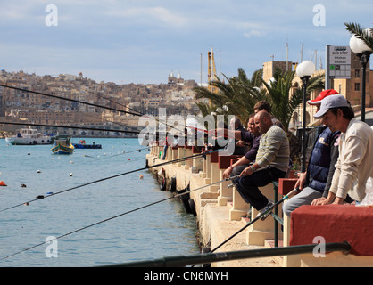 Eine Gruppe von Menschen Angeln, mit Stangen und Linien, innerhalb des Hafens in Kalkara, Malta, Europa Stockfoto