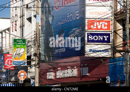 Viele Zeichen Werbung verschiedener Marken sind Teil der urbanen Landschaft oberhalb einer Stadtstraße in Chiang Rai, Thailand. Stockfoto