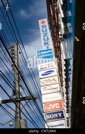 Viele Zeichen Werbung verschiedener Marken sind Teil der urbanen Landschaft oberhalb einer Stadtstraße in Chiang Rai, Thailand. Stockfoto