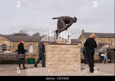 Leute stehen, suchen, wandern durch die Bronzestatue von cricketer Fred (Freddie) Trueman (schnell Bower Bowling) - Skipton, North Yorkshire, England, Großbritannien Stockfoto