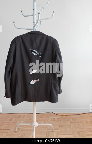 Wir finden Sie auf der Rückseite eines Mannes Jackett hängt eine Garderobe mit des April Dummkopfs Tages Fischen an der Jacke befestigt. Weiße Wand Stockfoto