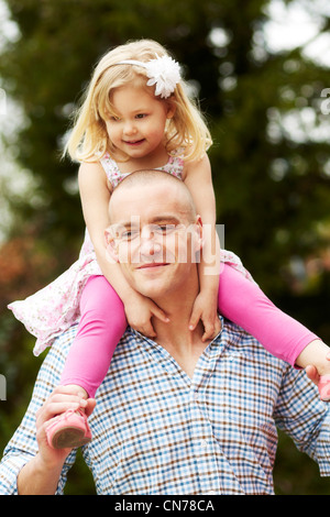 Mädchen setzte sich auf den Schultern der Väter Stockfoto