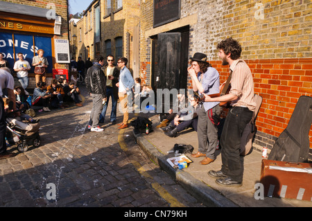 Zwei junge Buskers Gitarre spielen und singen auf der Straße, East London Stockfoto