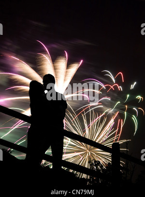 Eine Silhouette eines küssenden Paares vor einem riesigen Feuerwerk. Stockfoto