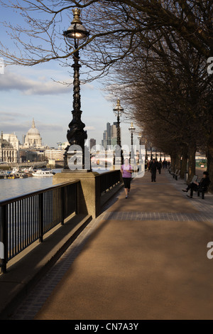 Thames mit St. Pauls und Millenium Fußgängerbrücke mit dem Themse-Ufer und die Skyline von London mit einem Jogger entlang der South Bank Stockfoto