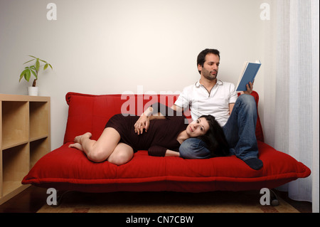 Glückliches junges Paar sitzt auf einem sofa Stockfoto