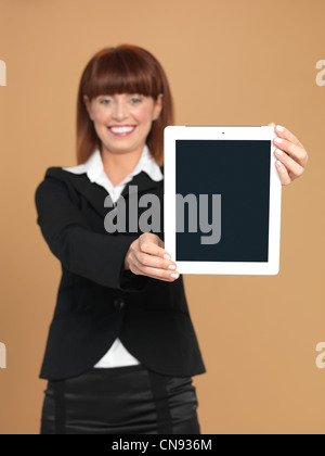 Porträt von eine schöne, junge Geschäftsfrau, zeigt eine elektronische Computer-Pad, lächelnd, auf Beige Hintergrund Stockfoto