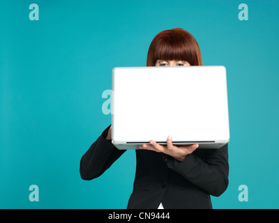 Porträt von eine schöne, junge Geschäftsfrau, hält einen Laptop vor ihr, mit ihren Augen zeigt auf blauem Hintergrund Stockfoto