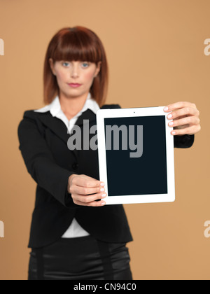 Porträt von eine schöne, junge Geschäftsfrau, zeigt eine elektronische Computer-Pad, lächelnd, auf Beige Hintergrund Stockfoto