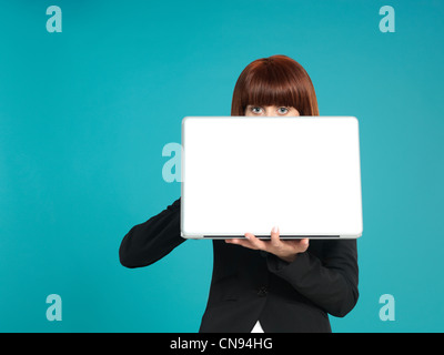 Porträt von eine schöne, junge Geschäftsfrau, hält einen Laptop vor ihr, mit ihren Augen zeigt auf blauem Hintergrund Stockfoto