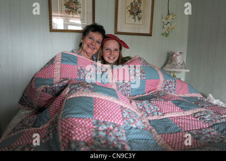 Großmutter und Enkelin kuschelten sich unter einer großen handgefertigten Decke Stockfoto