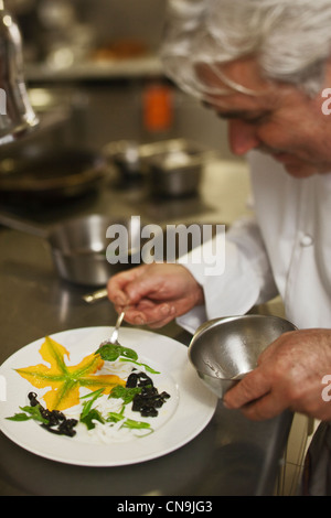 Frankreich, Alpes Maritimes, La Turbie, Bruno Cirino in der Küche und bereitet seinen Teller mit gegrillten Calamari, Zucchiniblüten, Stockfoto