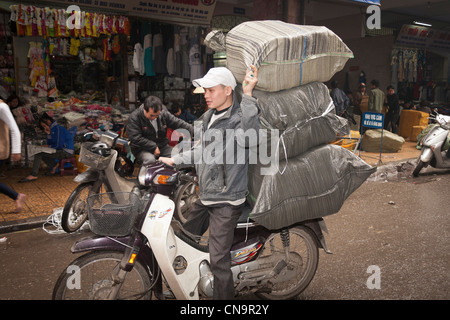 Mann, die Transport von großen Belastung des Rückens von seinem Motorrad in der Altstadt, Hanoi, Vietnam Stockfoto