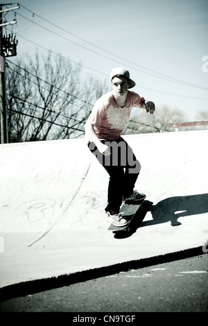 Porträt eines jungen Skateboarder Skaten eine Rampe hinunter. Stockfoto