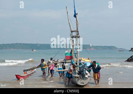 Angeln, Ausleger Katamaran startet bei Galle Sri Lanka Sri Lanka herausdrücken Fischer ihr Boot vom Ufer Stockfoto