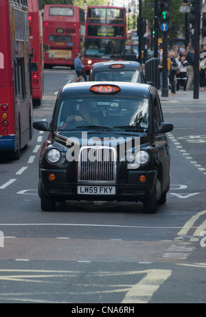 Die schwarzen Londoner Taxis bereit, mit Bussen in London, England. Stockfoto