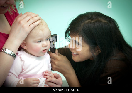 Eine Ärztin untersucht ein junges Mädchen mit einem Otoskop UK Stockfoto