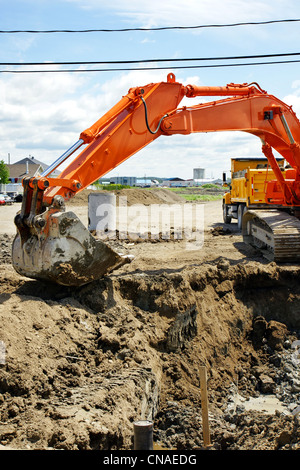 Mechanischen Bagger Graben große Bau Loch für Abwasser- und Wasserleitungen in die ländliche Entwicklung neuer Stockfoto