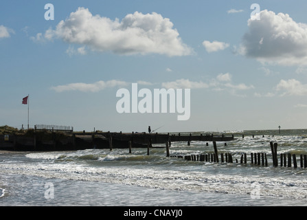 Einsamen Fischer am Strand von West Wittering mit Buhnen (Meer Verteidigung gegen Erosion) während einer Springflut high Stockfoto