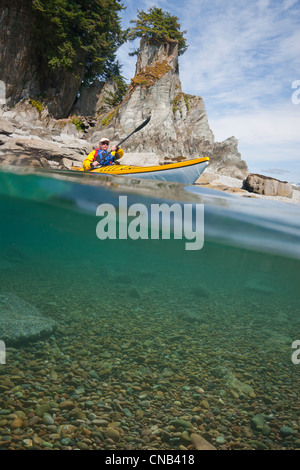 Wasserstand Blick auf ein Kajakfahrer Meer paddeln in ruhigen Gewässern entlang einer Küstenlinie in der Nähe von Juneau, Inside Passage, Alaska Stockfoto