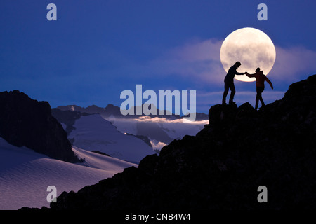 Zusammensetzung: Wanderer Silouetted auf einem Bergrücken oberhalb der Juneau Eisfeld mit dem Vollmond im Hintergrund, südöstlichen Alaska Stockfoto