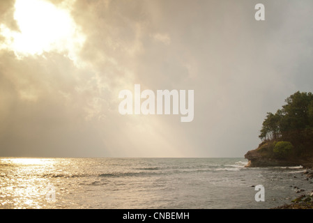 Goldenes Sonnenlicht funkelt auf der Oberfläche des Meeres neben natürliche Küstenlinie Stockfoto