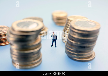 Miniatur-Abbildung eines Geschäftsmannes umgeben Euro-Münzen Stockfoto