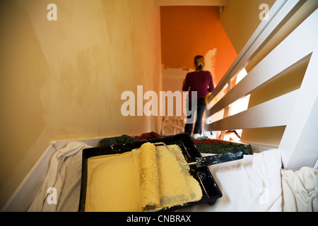 Lady, Frau Halle und Treppe Malerei Wände mit Bürstenwalze in der Nähe ändern Farbe Fokus auf Walze zu verzieren Stockfoto