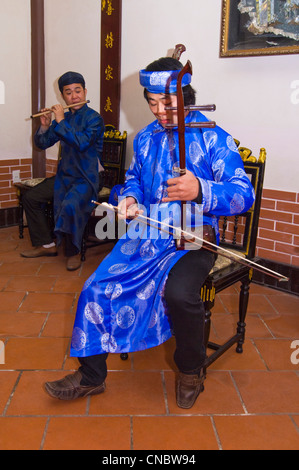 Vertikale Nahaufnahme des traditionellen vietnamesischen Musiker spielt die Dan nhi oder vertikale Violine in hellen bunten Kostümen. Stockfoto