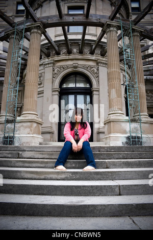 Eine junge Latin-Frau sitzen auf den Stufen eines alten Herrenhauses. Stockfoto