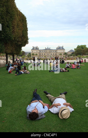 Frankreich, Paris, Jardin du Luxembourg (Jardin du Luxembourg), Menschen auf dem Rasen im Sommer, Senat im Hintergrund Stockfoto