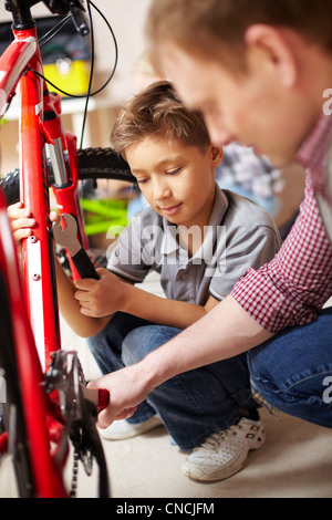 Porträt von kleinen Jungen und seinem Vater Reparatur Fahrrad in garage Stockfoto