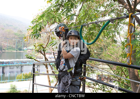 Ein Junge, der sich bereit macht, eine Seilrutsche hinunterzurutschen, Chiang Mai Zoo, Chiang Mai, Thaialnd Stockfoto