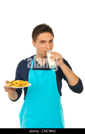 Mann in der Küche tragen blaue Schürze Milch und Kekse auf Platte isoliert auf weißem Hintergrund Stockfoto