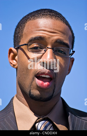 Afroamerikanische Mann mit Brille und einem Business-Anzug über einen blauen Himmelshintergrund isoliert. Stockfoto