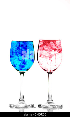 Zwei Gläser Wein mit Wasser gefüllt und Verbreitung rote und blaue Tinte Stockfoto