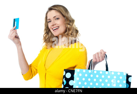 Attraktive Frau mit Kartenguthaben-Karte mit Einkaufstüten lächelnd vor weißem Hintergrund Stockfoto