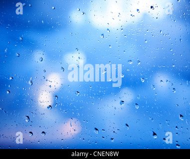 Fensterglas mit abstrakten Hintergrund Regentropfen, blau über blau bedecktem Himmel Stockfoto
