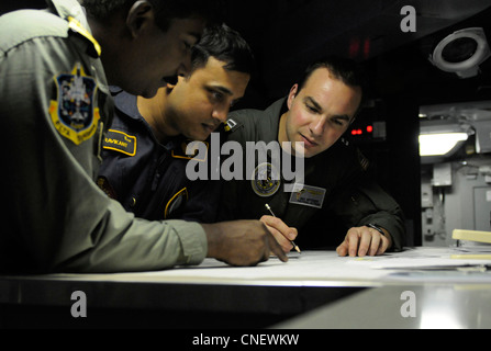 Taktischer Action Officer LT. Dan Mitzner, rechts, überprüft ein Übungsszenario im Unterseekriegmodul im Kampfrichtungszentrum an Bord des Nimitz-Klasse Flugzeugträgers USS Carl Vinson (CVN 70) mit den indischen Marine-Verbindungsoffizieren Cmdr. Ajay Daniel Theophilus, links, und LT. Cmdr. Madhavdas Ravikant. Carl Vinson und Carrier Air Wing (CVW) 17 sind an der Übung Malabar 2012 mit Schiffen und Flugzeugen der indischen Marine beteiligt. Stockfoto