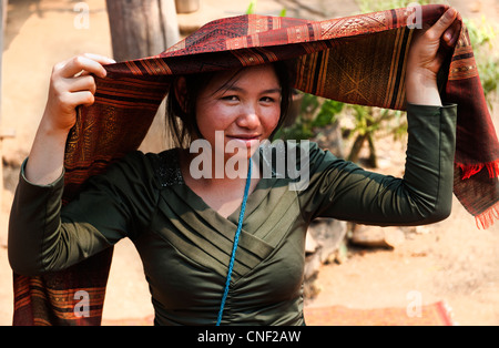 Lächelnde junge Frau vom Dorf in der Nähe des Mekong in Laos mit lokal produziert Gewebe zum Schutz vor der Sonne Stockfoto