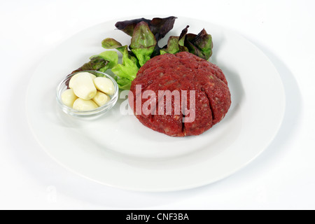 Steak Tartar mit Knoblauch auf weißen Teller mit Zwiebeln und Ketchup. Stockfoto