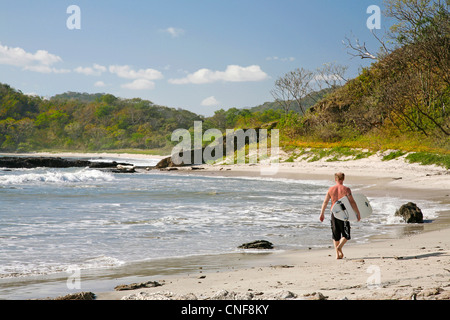 Madera-Strand in der Nähe von San Juan del Sur Nicaragua Pazifik Surfer zu Fuß am Sandstrand mit Surfbrett auf sonnigen Tag blauer Himmel Stockfoto