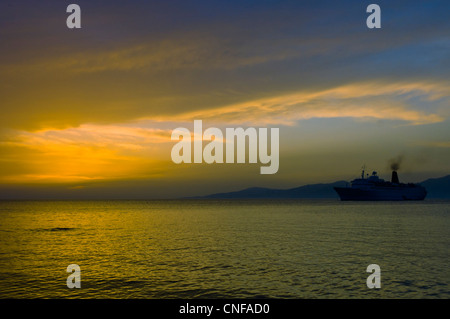 Sonnenuntergang am Ägäischen Meer mit Kreuzfahrt Schiff Silhouette in Hafen von Mykonos, Griechenland Stockfoto