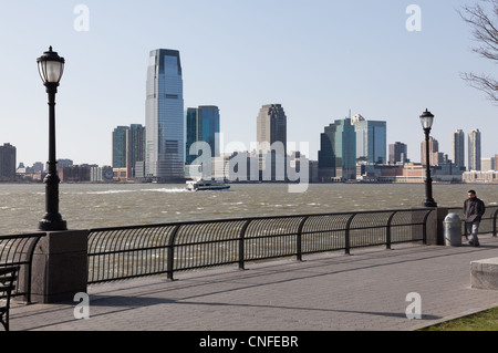 NEW YORK, USA - März 26: Mann zu Fuß windigen NY am Flussufer auf 26. März 2012. Goldman Sachs Turm erhebt sich 548 Füße. Stockfoto