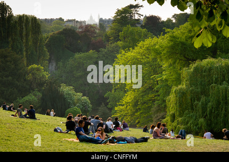 Menschen entspannen auf dem Rasen und grüne Hügel Buttes-Chaumont Park, Paris, Frankreich Stockfoto