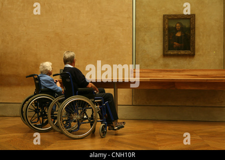 Behinderte Besucher im Rollstuhl geniessen das Porträt der Mona Lisa von Leonardo da Vinci im Louvre in Paris, Frankreich. Stockfoto