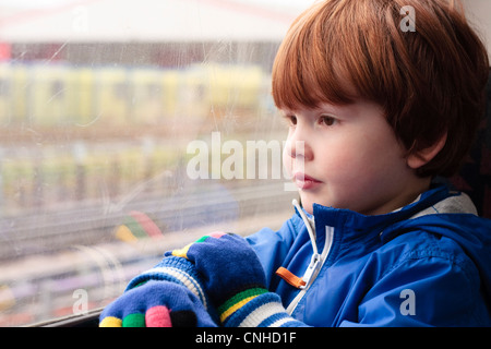 Ein kleiner Junge (drei Jahre) blickt aus dem Fenster, während der Reise im Zug Stockfoto