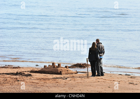 Konzept. Junger Mann und Frau stehen neben eine Sandburg am Strand gebaut und die Zukunft gemeinsam zu betrachten. Stockfoto