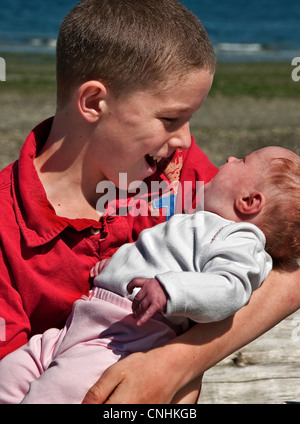 großen Bruder halten und die Interaktion mit seinem Babyschwester, in denen sie auf seine Liebe reagiert, zu lieben. Kaukasische Familie Stockfoto