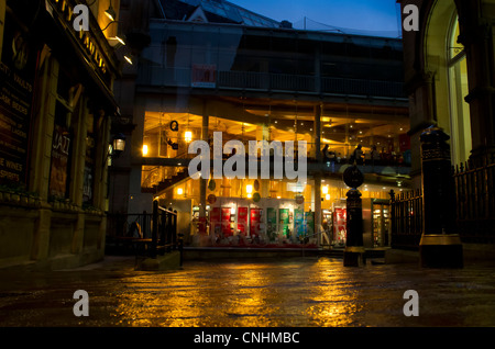 Warme Orange Licht aus Waterstones und Starbucks in Bradford Wolle Austausch, Reflexion über Pflastersteine in der Abenddämmerung. Stockfoto